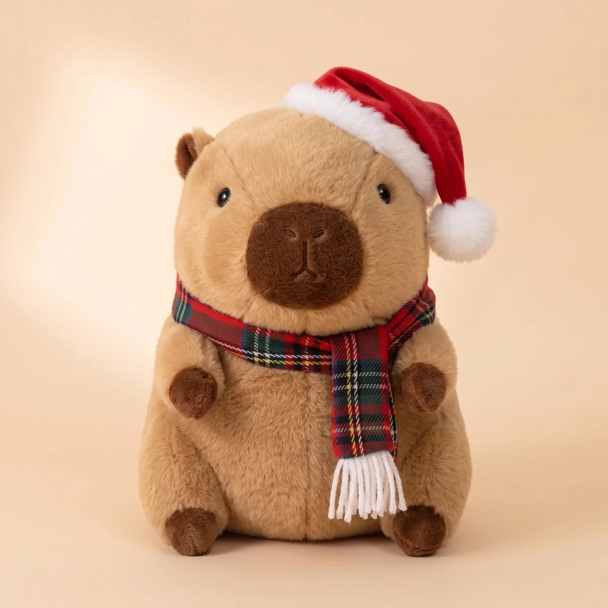 Front view of the Christmas capybara plush with a Santa hat and a red tartan scarf