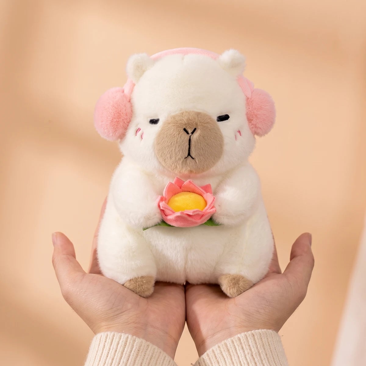 10 in white headphones capybara plush held in two hands