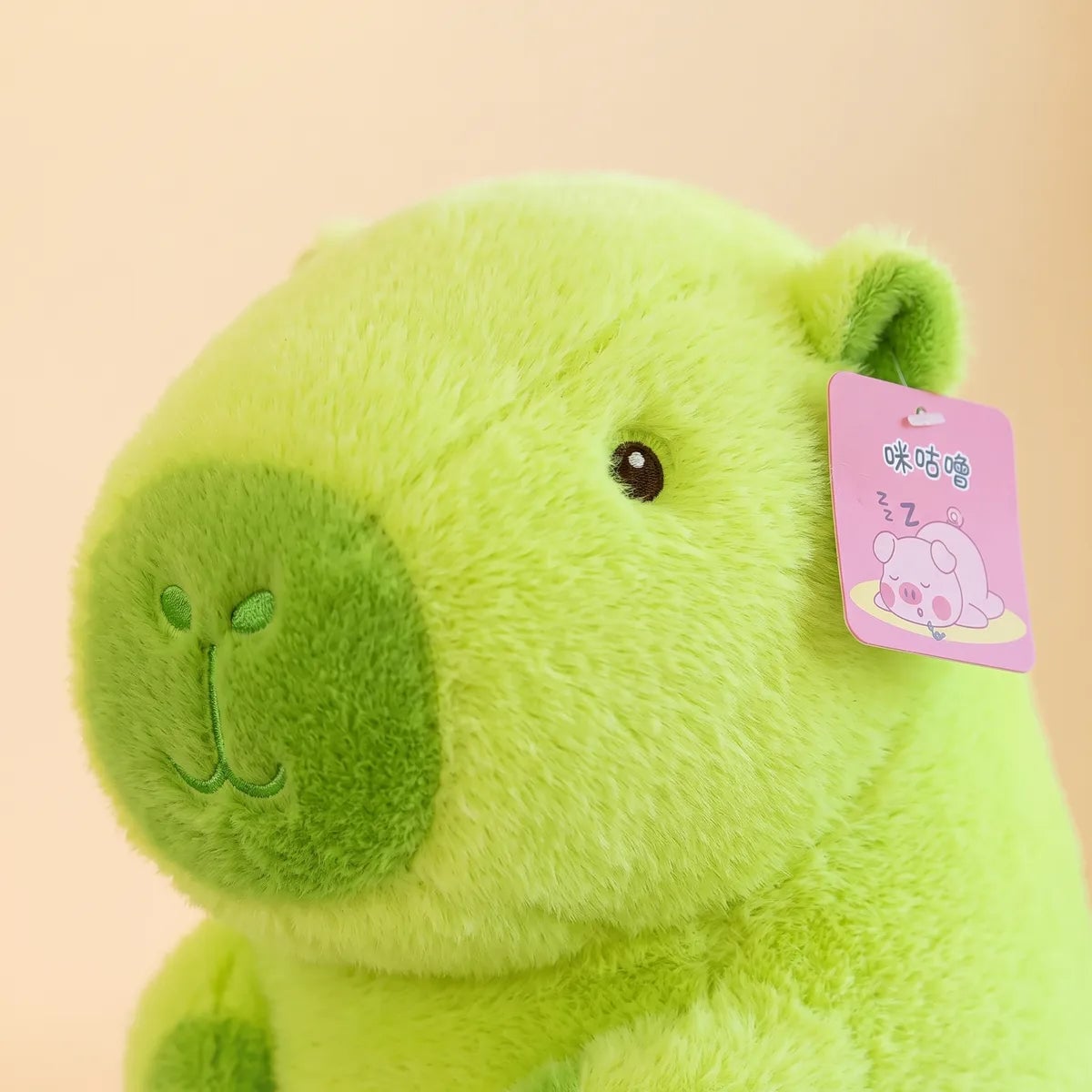 Close up of the banana capybara plush face with amber eyes and a dark green muzzle