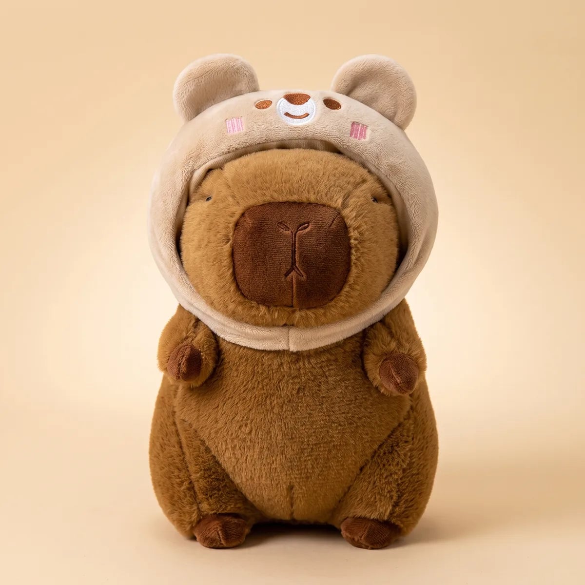 Brown bear capybara plush seen from the front in its cream teddy hood