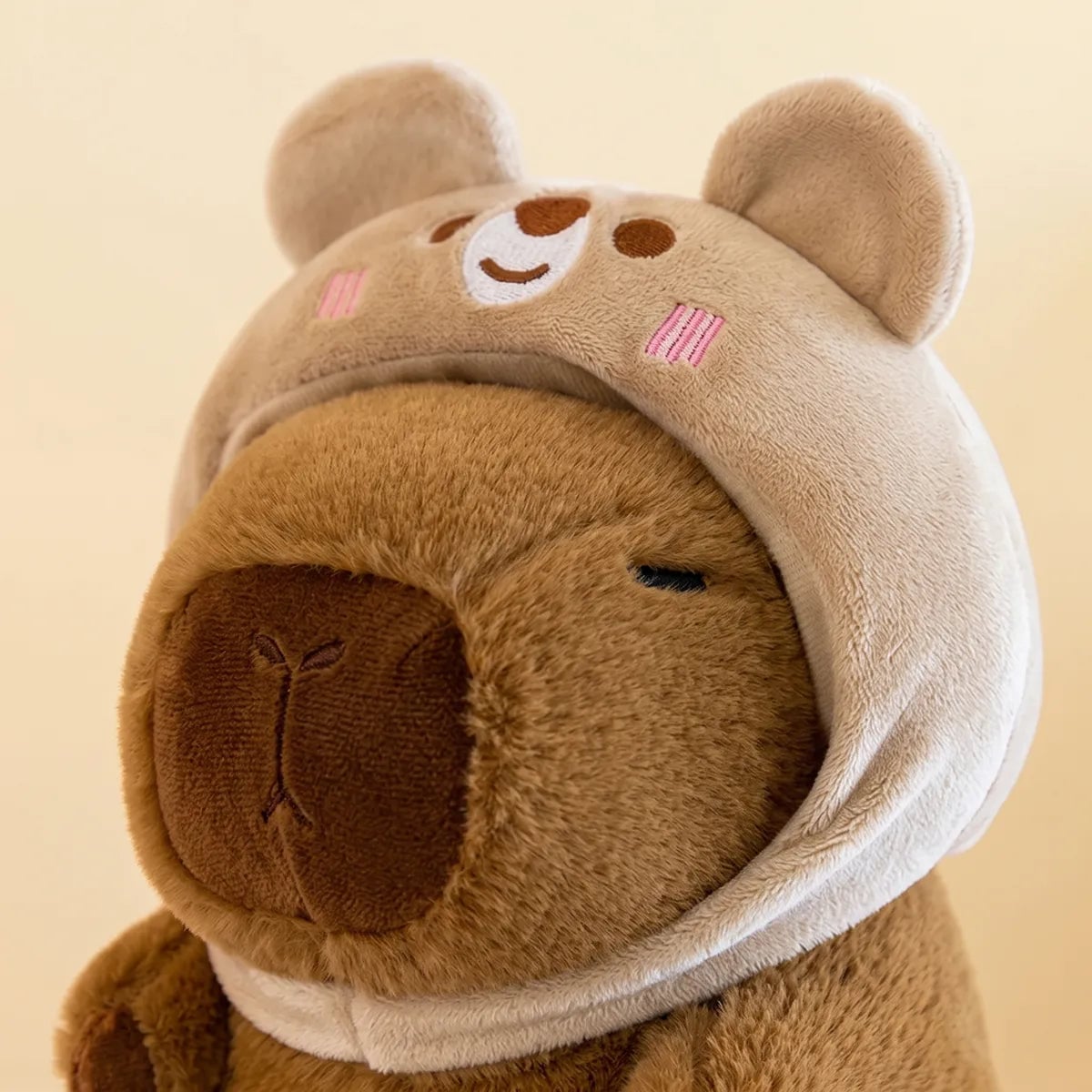 Close up of the embroidered bear face on the hood of the capybara plush
