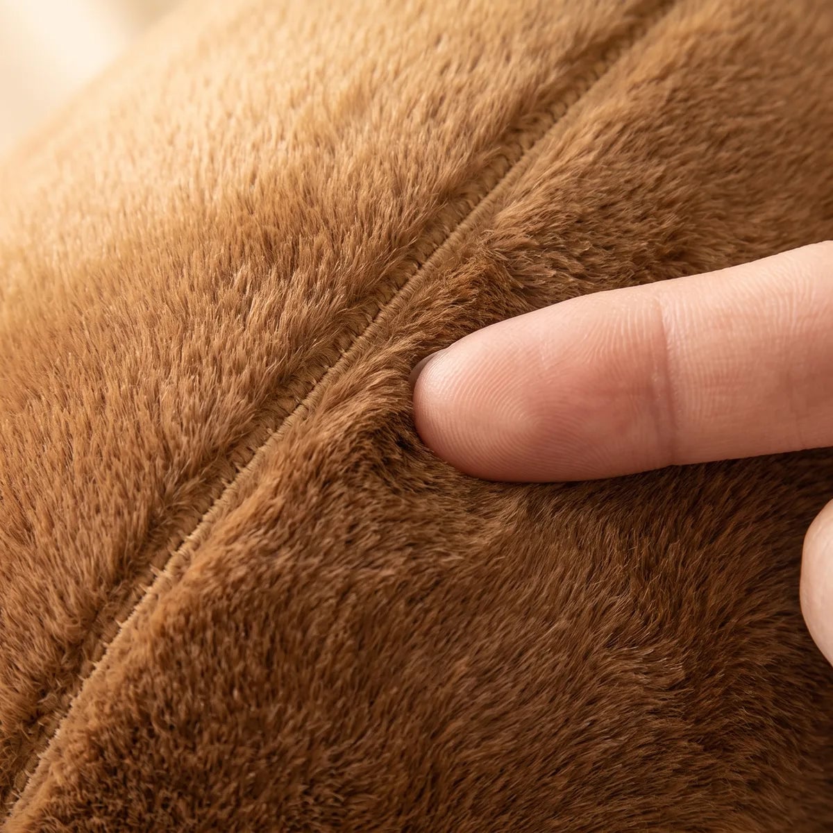 Fingertip pressing into the dense caramel brown pile of the capybara snot plush