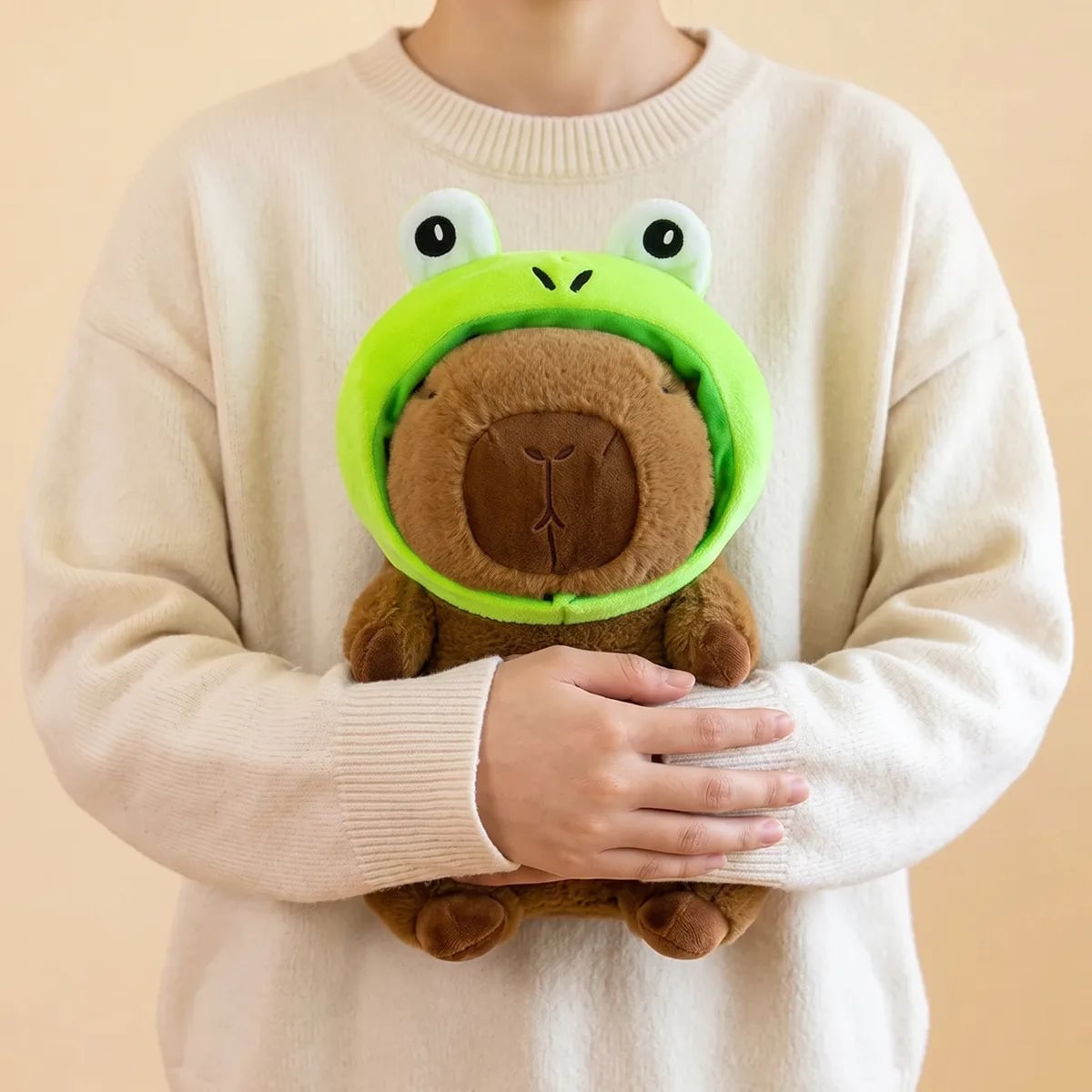 Person hugging the frog capybara plush against a sweater