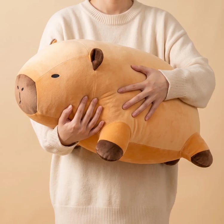 Person holding the giant capybara plush to show its real size