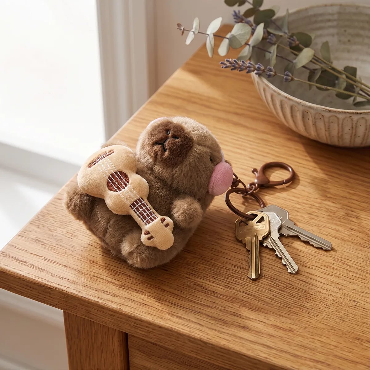 Guitar capybara keychain lying on a wooden table