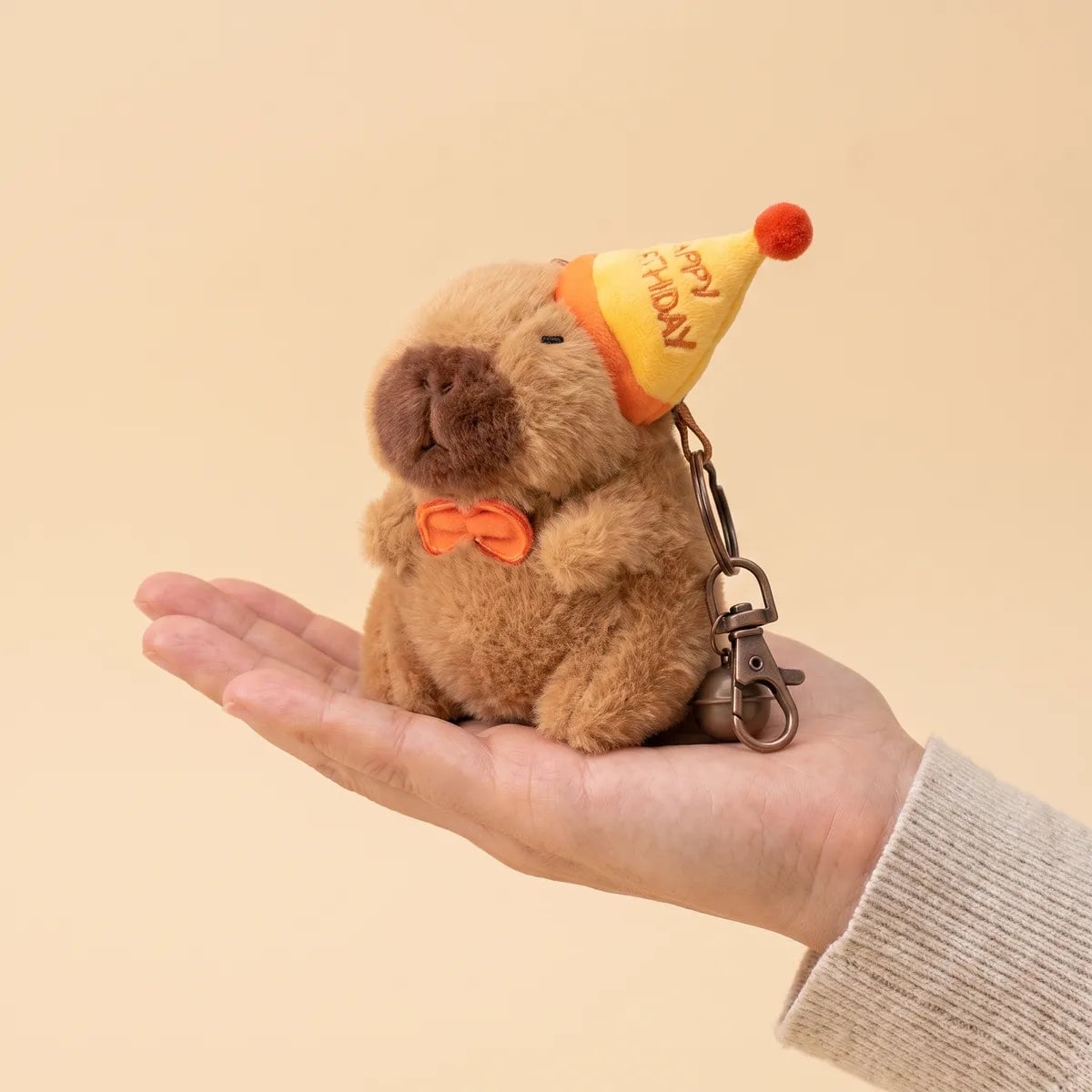 Birthday capybara keychain resting on an open palm to show its 4 in body