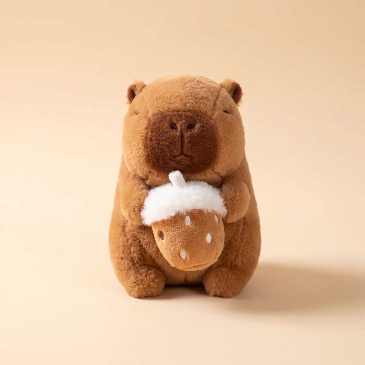 Front view of the 5 in hazelnut mini capybara plush wearing no costume and holding its plush nut