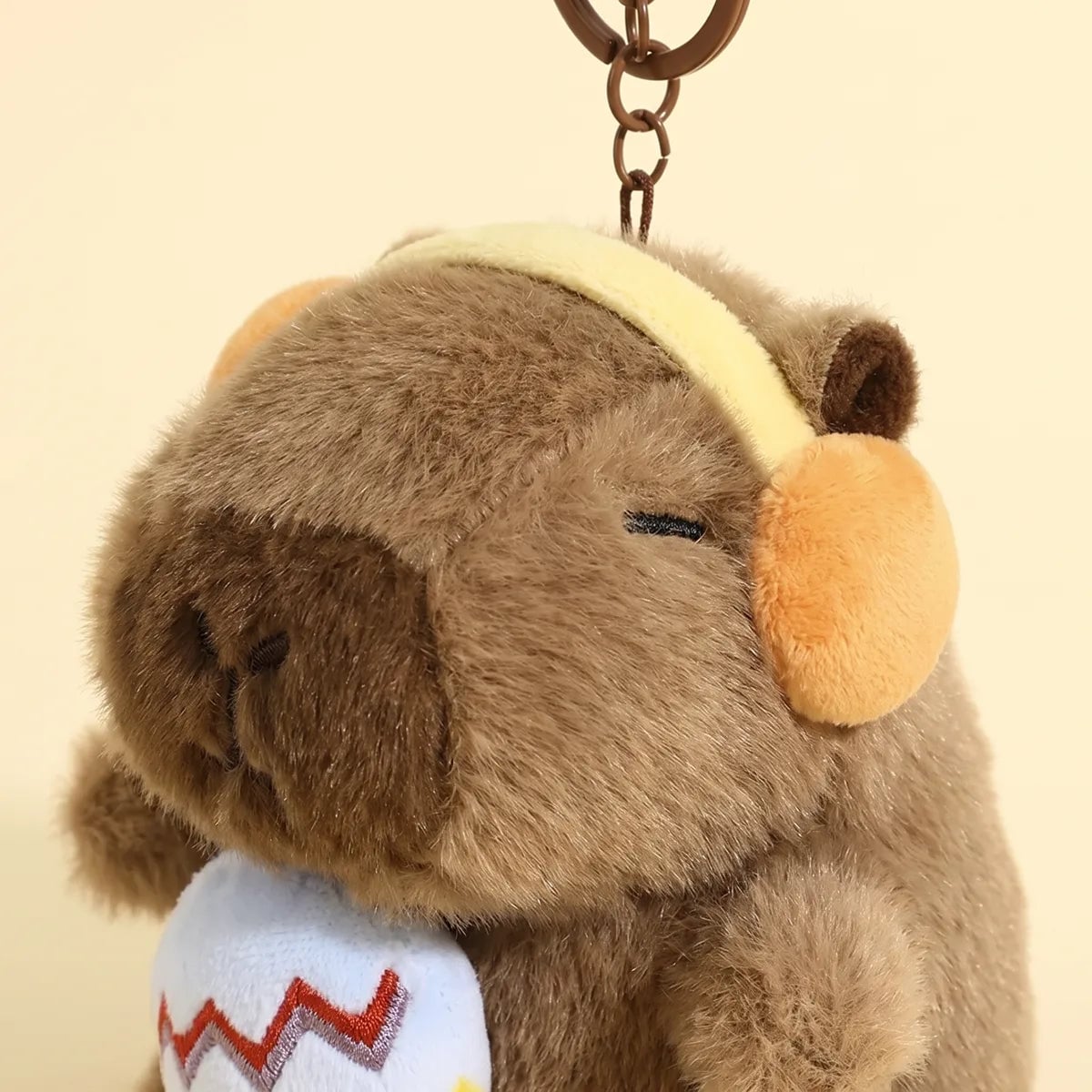 Close up of the embroidered microphone and ear cups on the capybara keychain
