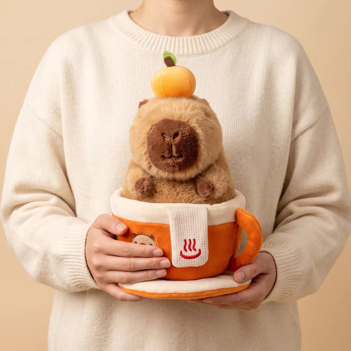 Person holding the orange coffee cup capybara plush