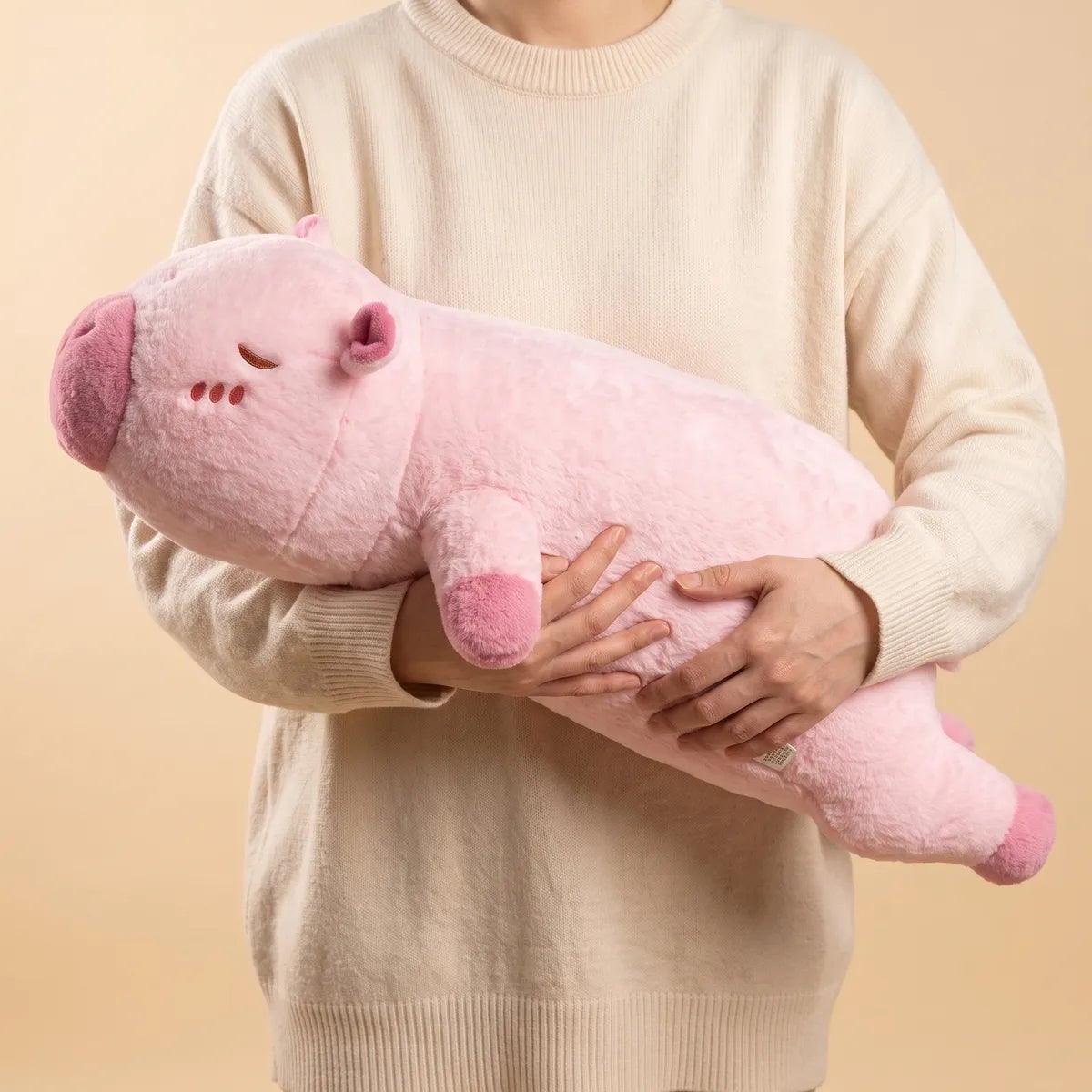 Person holding the pink pillow giant capybara plush to show its length