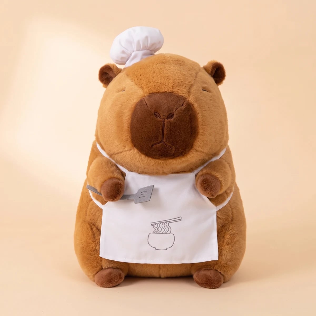 Front view of the ramen chef capybara plush with a white chef hat, apron and spatula