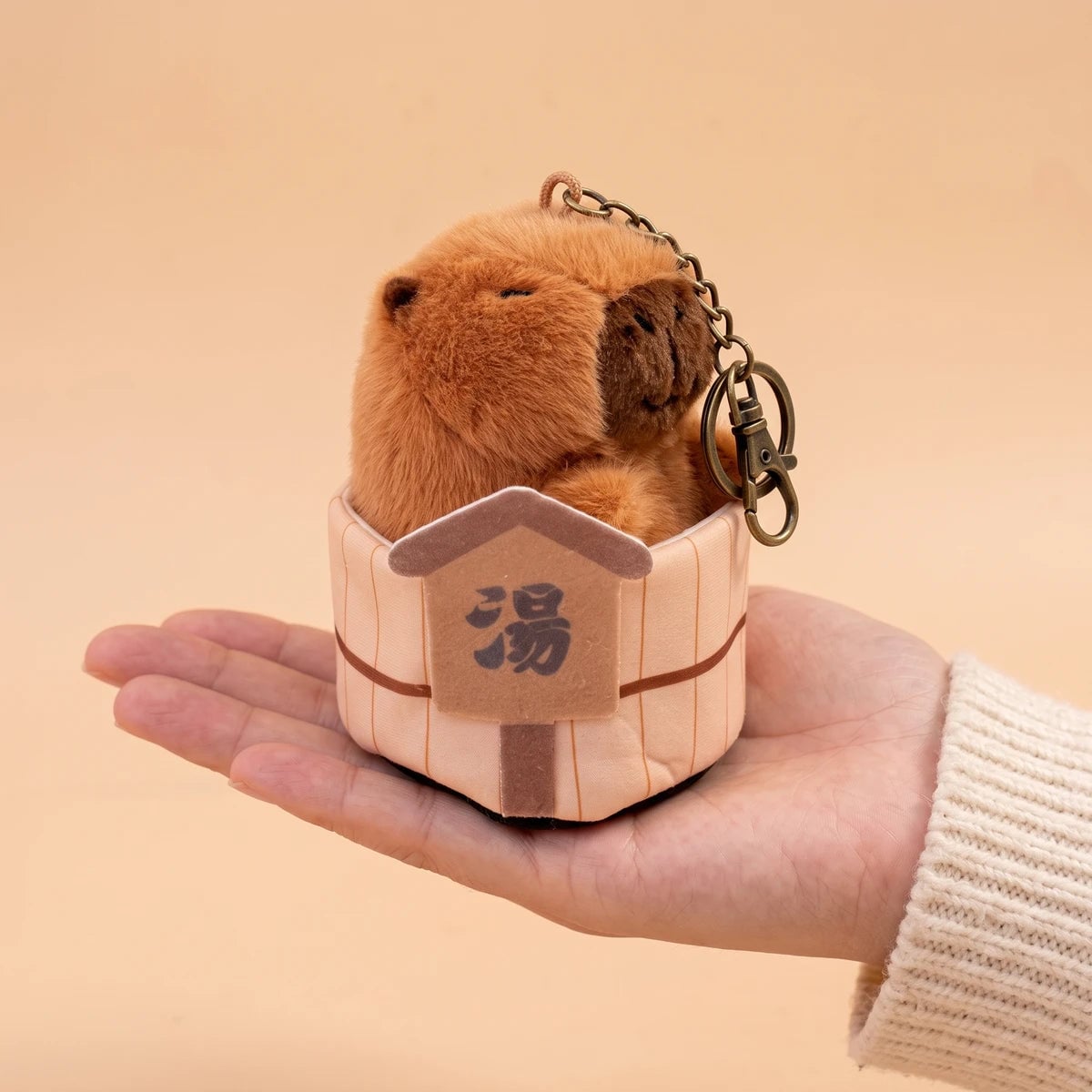Onsen capybara keychain resting on an open palm to show its 6 in size