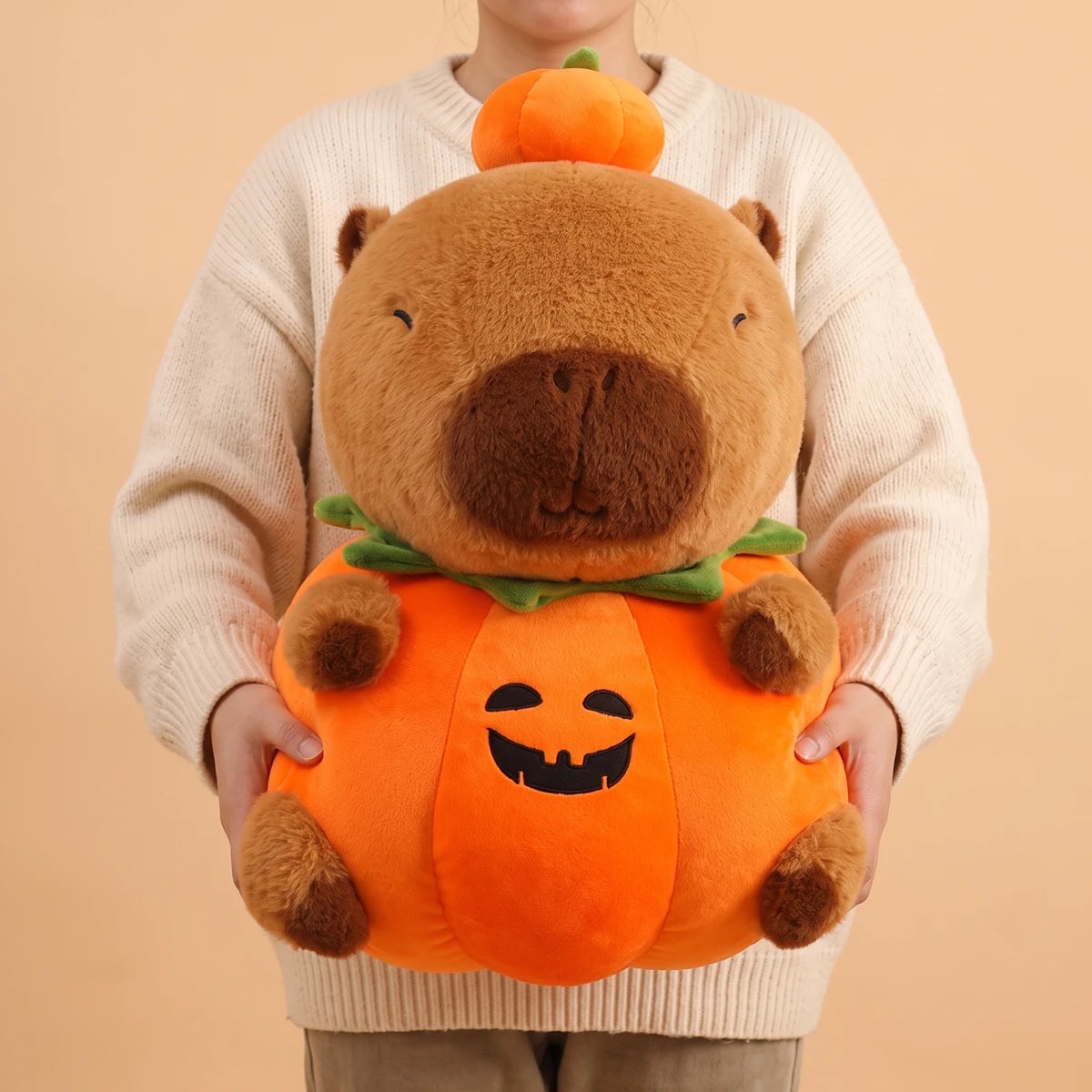 Person holding the 24 in pumpkin capybara plush in front of their chest
