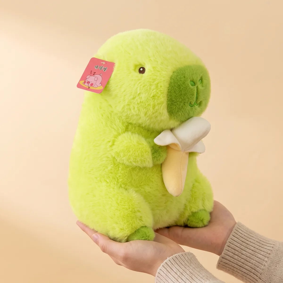 Banana capybara plush held in one hand to show its 9 in height
