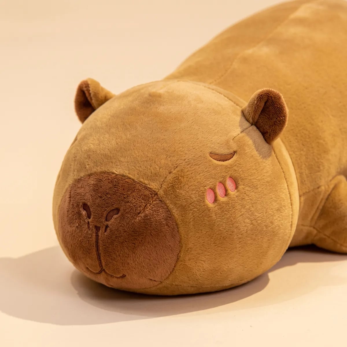 Close up of the closed eye and blush marks on the brown capybara pillow plush