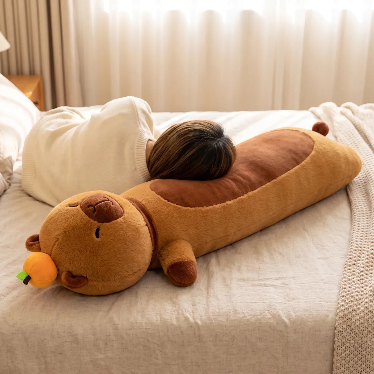 Person resting against the capybara body pillow plush to show its length