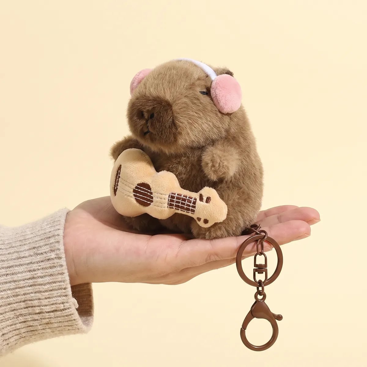 Guitar capybara keychain held in a hand to show its 4 in size
