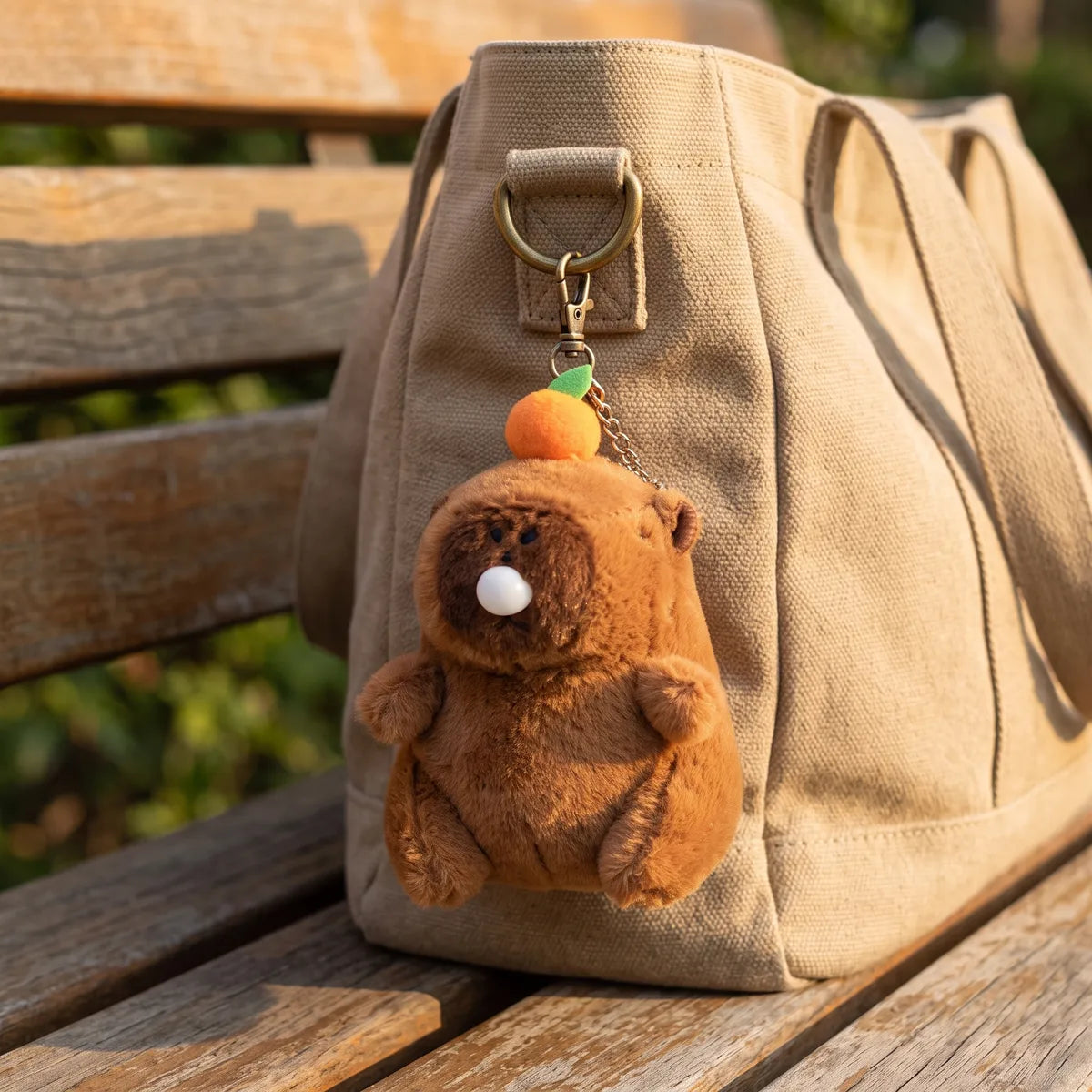 Capybara keychain plush blowing a bubble, clipped to a canvas tote bag